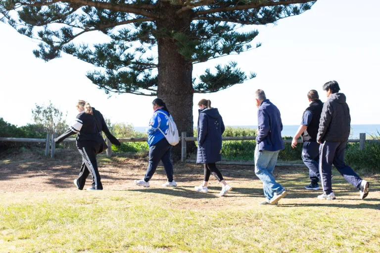 Day program group walking together along a coastal park