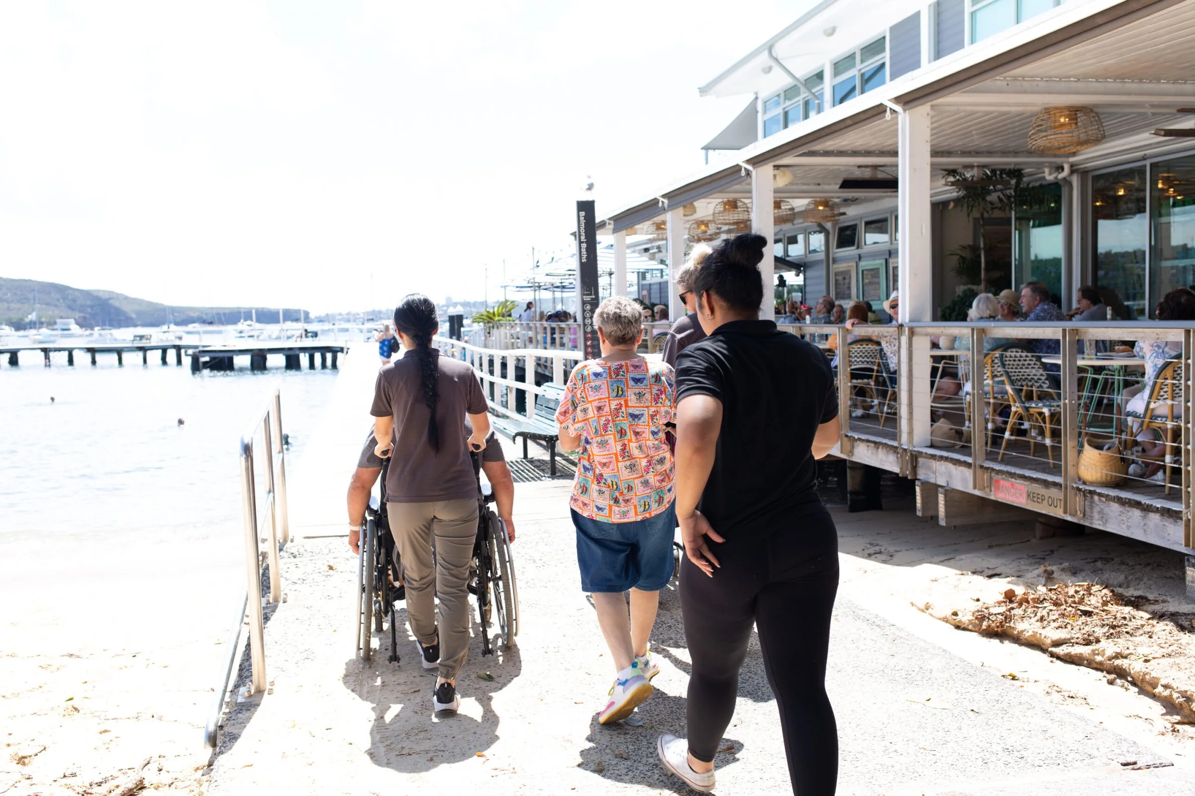Support workers walking with a participant along a waterfront walkway